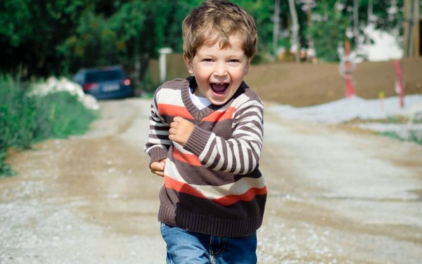 طفل في مرحلة الطفولة المتوسطة يركض فرحًا.