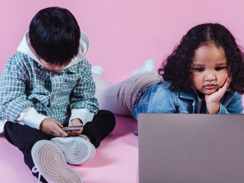 طفل وطفلة يستخدمان أجهزة إلكترونية، كيف يمكن وقايتهما مخاطر الإنترنت؟